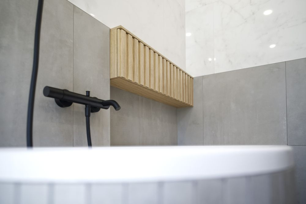 Realizace minimalistické koupelny – velkoformátové obklady a dlažba v dokonalých imitacích, asymetrická vana i sprcha bez vaničky 10